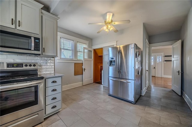 kitchen featuring backsplash, baseboards, appliances with stainless steel finishes, and ceiling fan