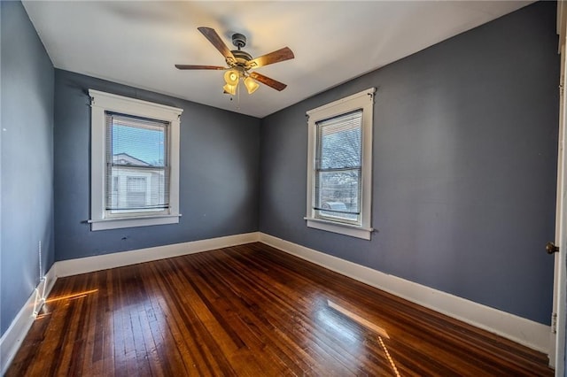 unfurnished room featuring baseboards, dark wood-style floors, and a ceiling fan