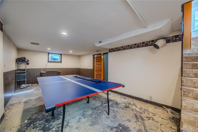 recreation room featuring unfinished concrete floors, wooden walls, a wainscoted wall, visible vents, and recessed lighting