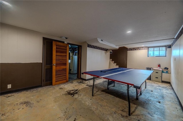 rec room with unfinished concrete flooring and water heater