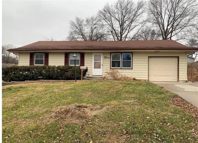 ranch-style home featuring entry steps, an attached garage, concrete driveway, and a front yard