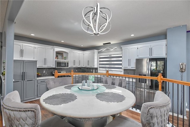 11705 E 86th Ter, Raytown, MO 64138 - dining room featuring a chandelier, wood finished floors, recessed lighting, and plenty of natural light