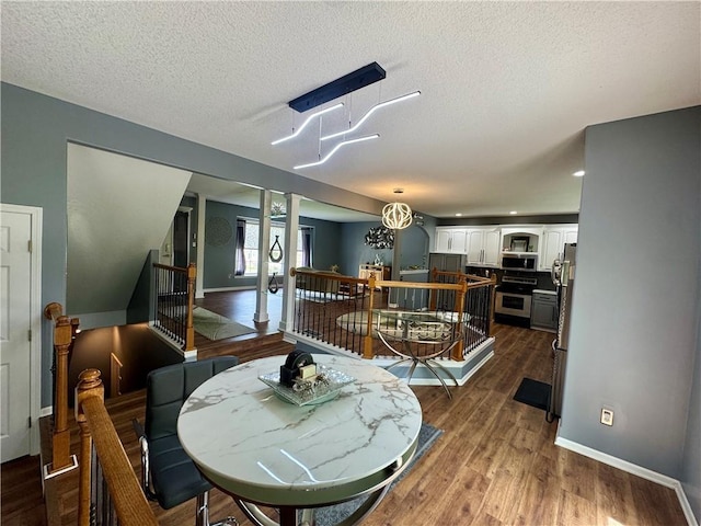 11705 E 86th Ter, Raytown, MO 64138 - dining room with wood finished floors, baseboards, a textured ceiling, and decorative columns
