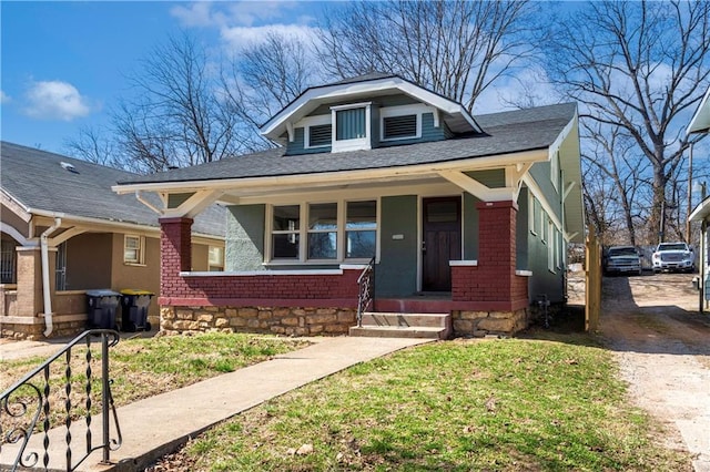 bungalow with a porch, driveway, and a front lawn