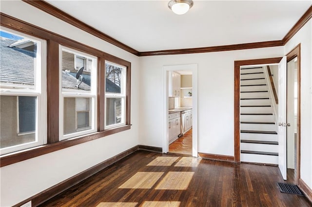 interior space with dark wood-style flooring, visible vents, baseboards, and ornamental molding