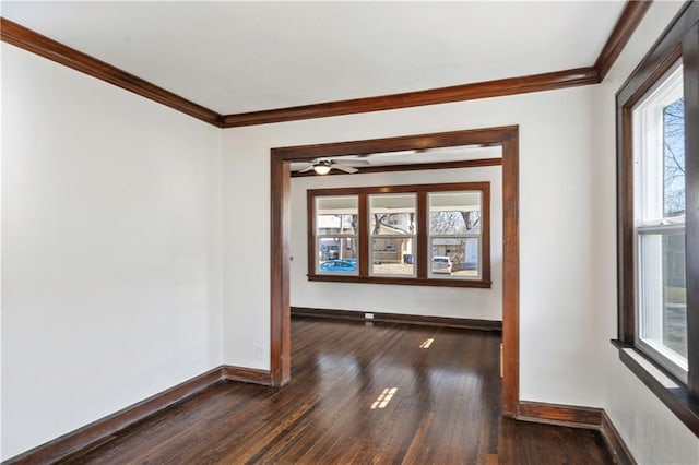 spare room with dark wood finished floors, a ceiling fan, crown molding, and baseboards