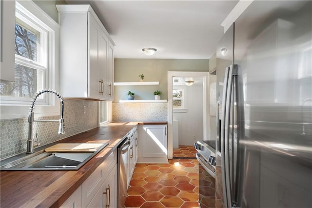 kitchen with a sink, wood counters, plenty of natural light, and appliances with stainless steel finishes