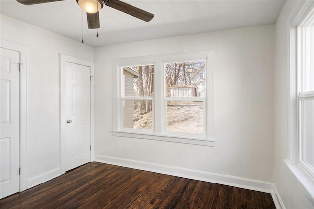 spare room featuring dark wood-type flooring, a ceiling fan, and baseboards