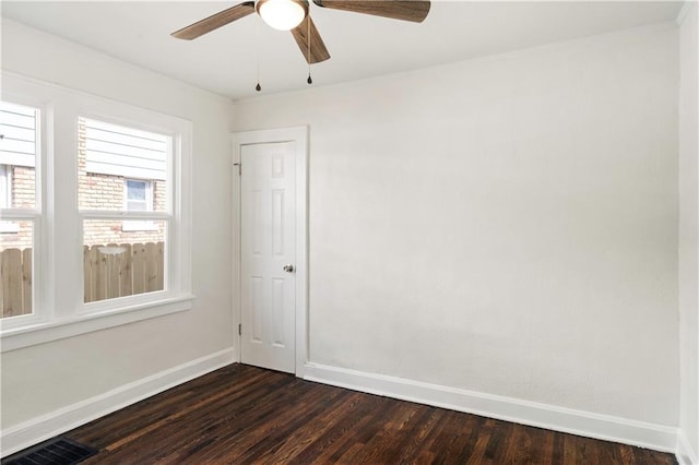 unfurnished room with dark wood finished floors, visible vents, a ceiling fan, and baseboards