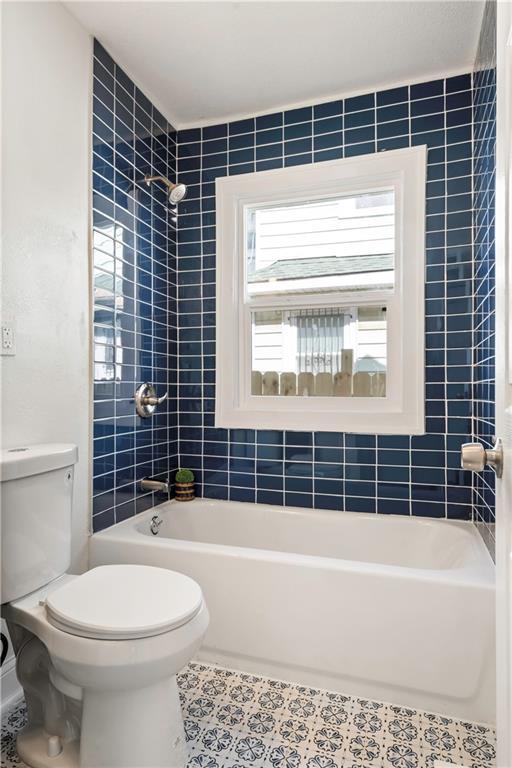 full bathroom with shower / bathing tub combination, toilet, and tile patterned flooring