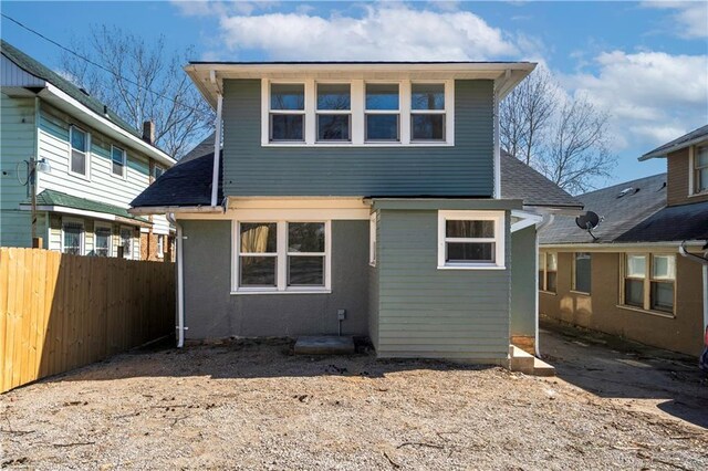 rear view of house featuring fence and a shingled roof