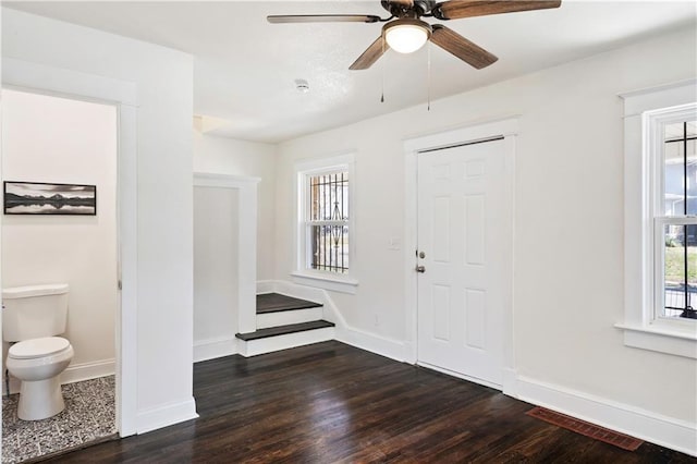 foyer entrance featuring visible vents, wood finished floors, stairway, baseboards, and ceiling fan