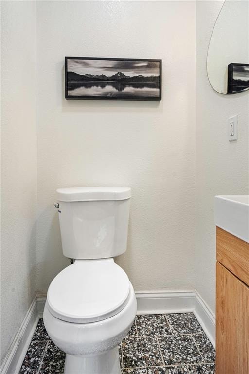 bathroom featuring toilet, vanity, and baseboards