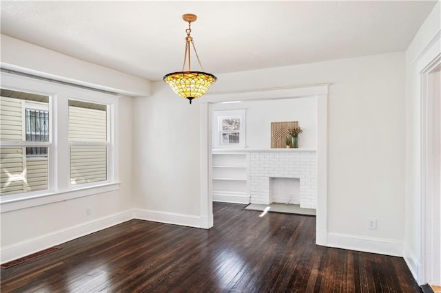 unfurnished dining area featuring a brick fireplace, dark wood-type flooring, and baseboards