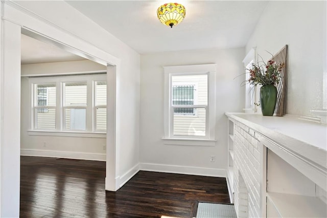 corridor featuring a wealth of natural light, baseboards, and dark wood-style floors