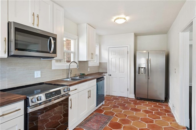 kitchen featuring a sink, white cabinets, appliances with stainless steel finishes, backsplash, and butcher block counters