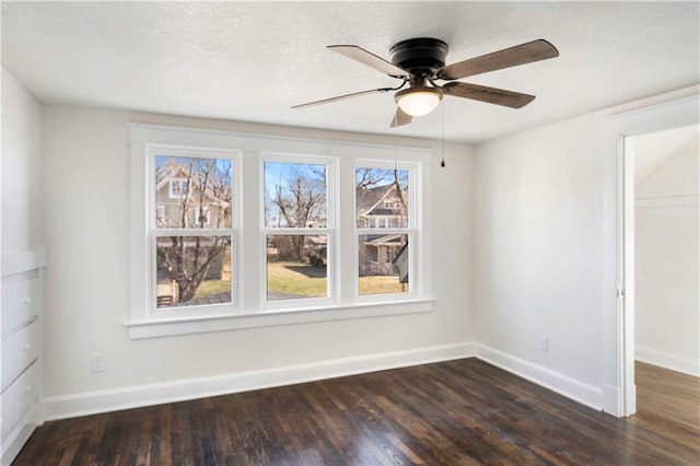 empty room with baseboards, dark wood finished floors, and a ceiling fan