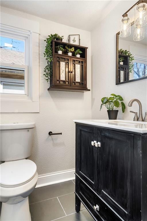 half bath with baseboards, toilet, vanity, and tile patterned flooring