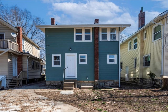 back of property with entry steps and a chimney