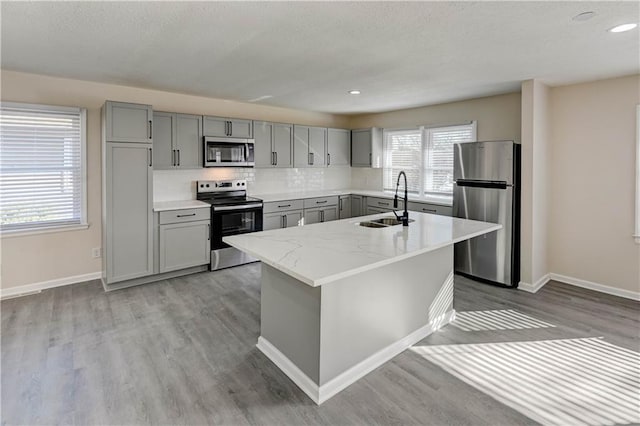 kitchen featuring a sink, stainless steel appliances, gray cabinetry, and light wood finished floors