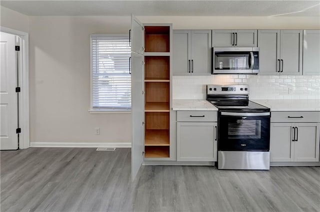 kitchen featuring visible vents, open shelves, gray cabinetry, appliances with stainless steel finishes, and tasteful backsplash