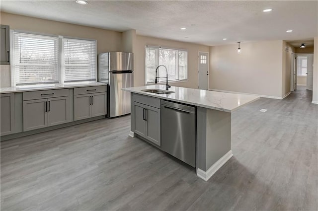 kitchen featuring a sink, light wood-style floors, appliances with stainless steel finishes, and gray cabinetry