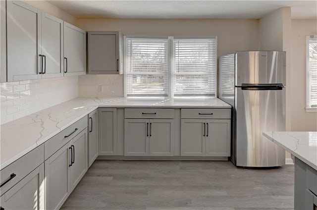 kitchen featuring backsplash, plenty of natural light, freestanding refrigerator, and gray cabinetry