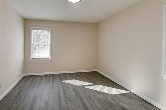 unfurnished room featuring baseboards and wood finished floors