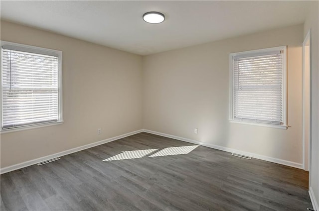 spare room with visible vents, baseboards, and wood finished floors