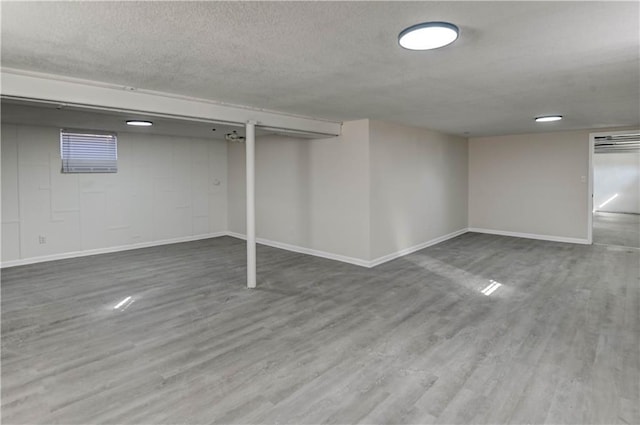 finished below grade area with wood finished floors, baseboards, and a textured ceiling