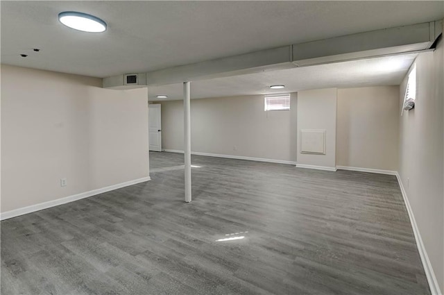 basement with wood finished floors, visible vents, and baseboards