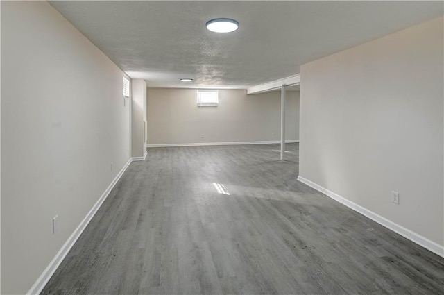 below grade area with wood finished floors, baseboards, and a textured ceiling