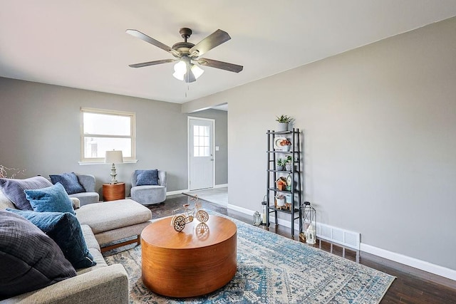 living area featuring wood finished floors, visible vents, baseboards, and ceiling fan