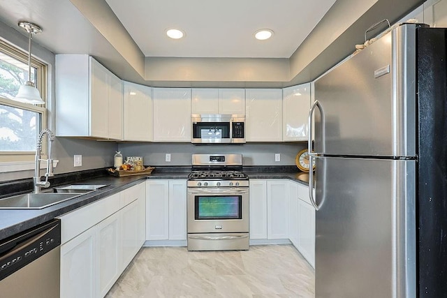 kitchen with a sink, dark countertops, white cabinetry, and stainless steel appliances