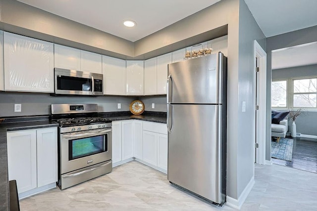 kitchen featuring dark countertops, white cabinets, baseboards, and appliances with stainless steel finishes