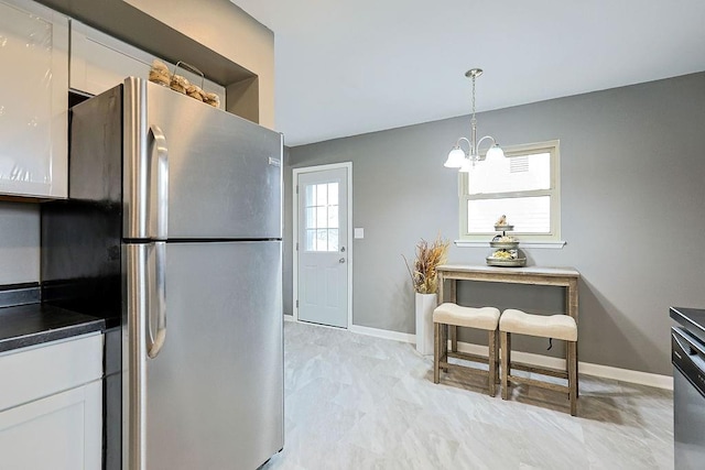 kitchen with white cabinetry, dark countertops, a chandelier, and freestanding refrigerator