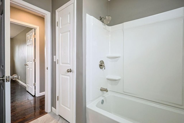 full bathroom featuring baseboards, wood finished floors, and  shower combination