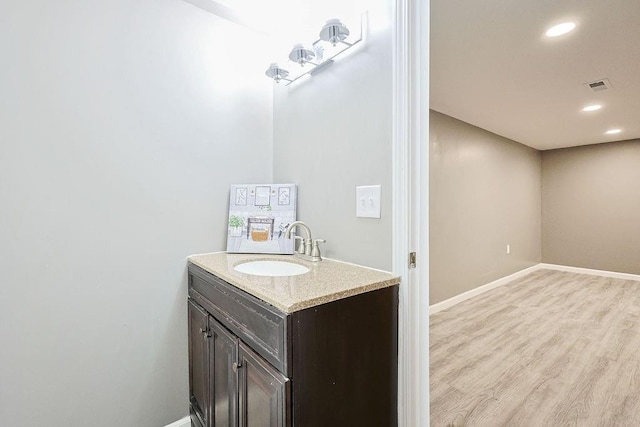 bathroom featuring visible vents, vanity, baseboards, and wood finished floors