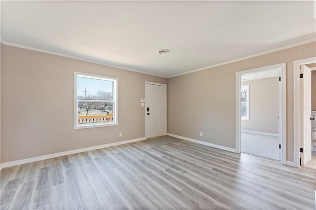 spare room with visible vents, baseboards, ornamental molding, and light wood finished floors