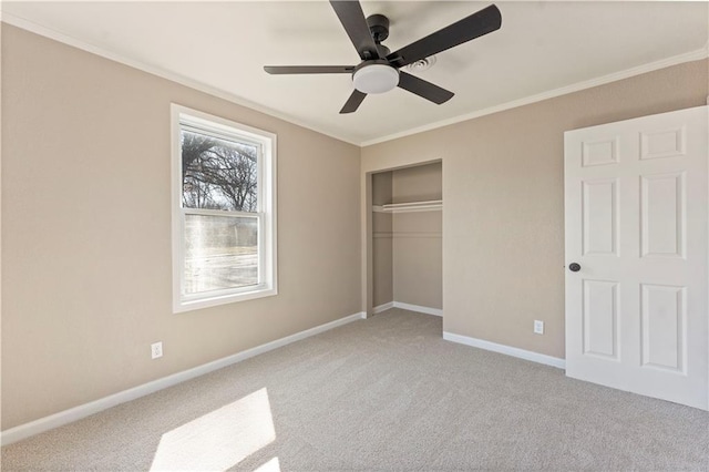 unfurnished bedroom featuring a closet, carpet floors, crown molding, baseboards, and ceiling fan