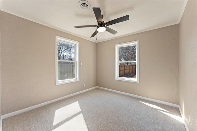 carpeted empty room with visible vents, a ceiling fan, baseboards, and ornamental molding