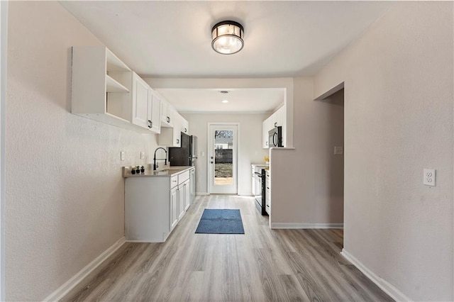 kitchen with baseboards, light countertops, light wood-type flooring, white cabinets, and open shelves