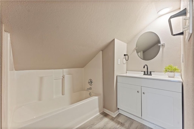 full bathroom with a tub to relax in, a textured ceiling, wood finished floors, a shower with shower curtain, and vanity