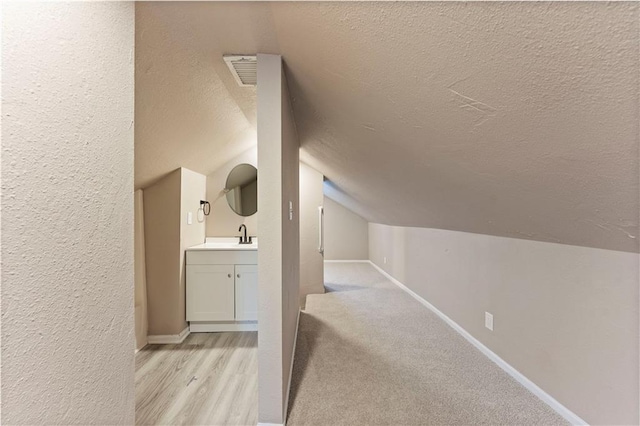 interior space with visible vents, baseboards, lofted ceiling, a textured ceiling, and a textured wall