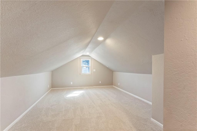 bonus room featuring vaulted ceiling, carpet, baseboards, and a textured ceiling