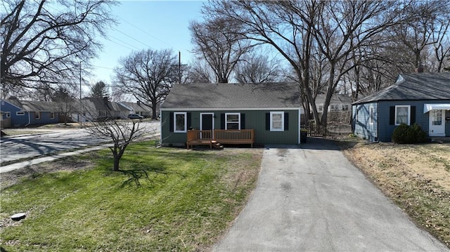 view of front of property with aphalt driveway, a wooden deck, and a front lawn