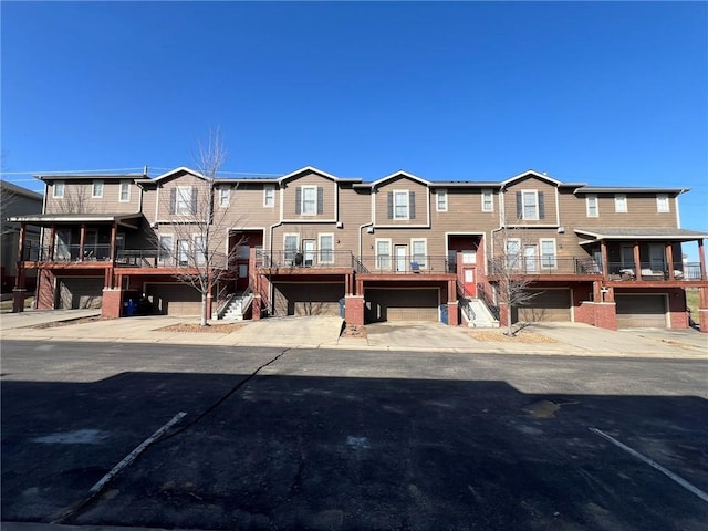 multi unit property with stairway, an attached garage, and driveway