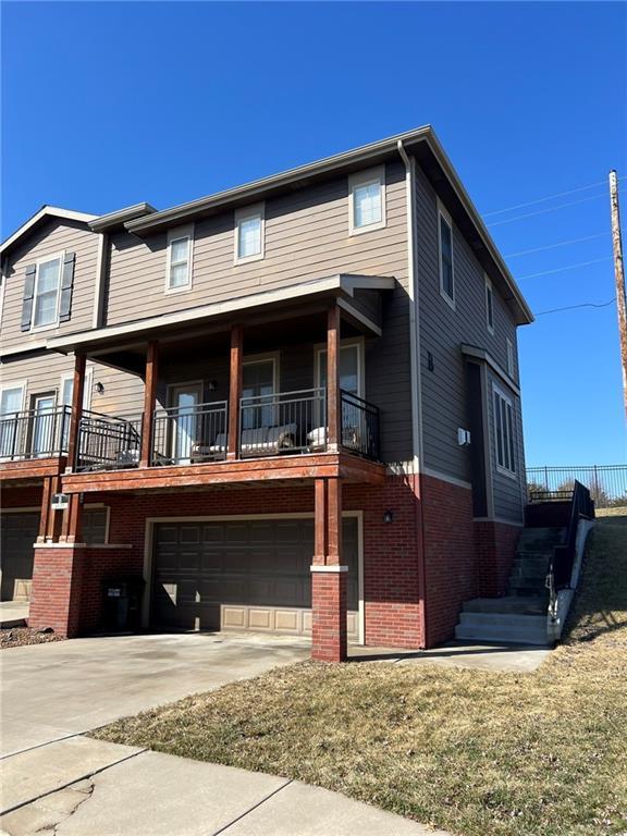 view of property featuring brick siding, concrete driveway, and an attached garage