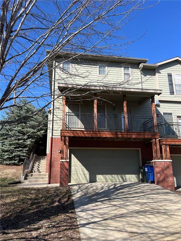 view of front of property with a balcony, brick siding, a garage, and driveway