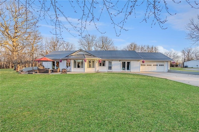 view of front of home with a front lawn, concrete driveway, metal roof, a garage, and a standing seam roof